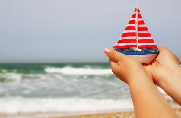 Woman's hands holding a boat in front of sea horizon — Stock Photo, Image