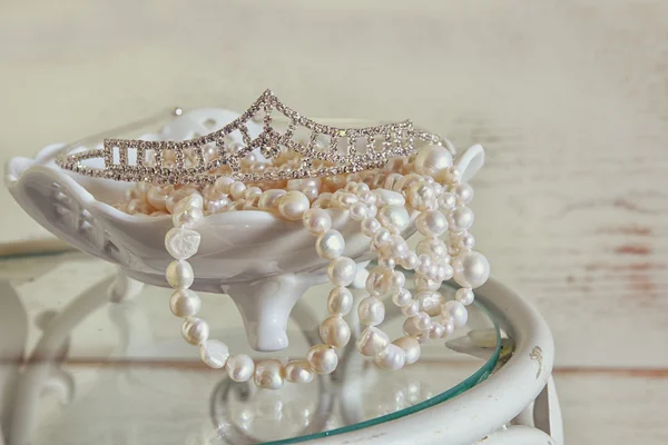 Image of white pearls necklace and diamond tiara on vintage table. vintage filtered. selective focus — Stock Photo, Image