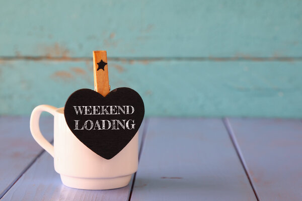 Tasse Kaffee und kleine herzförmige Kreidetafel mit der Aufschrift: Weekend Loading. — Stockfoto