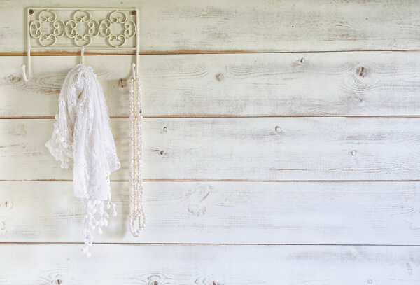 white pearls necklace and lace scarf hanging on wooden wall. selective focus.