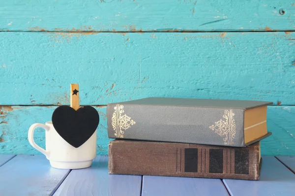 Kávéscsésze kis Hart alakú üres Chalkboard és verem a régi könyvek fából készült asztal. évjárat szűrés — Stock Fotó