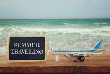 metin ile yazı tahtası yanında oyuncak uçak fotoğrafı yakın: yaz seyahat, deniz dalgaları karşı. Vintage filtre uygulanan görüntü, seçici odak