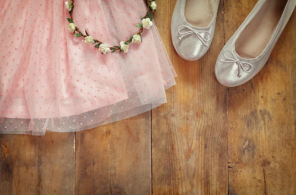 Abito vintage da bambina in chiffon, tiara floreale accanto alle scarpe da balletto su fondo in legno. immagine filtrata vintage — Foto Stock