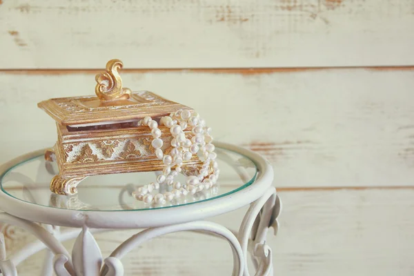 Imagem de colar de pérolas brancas e tiara de diamante na mesa vintage. vintage filtrado. foco seletivo — Fotografia de Stock