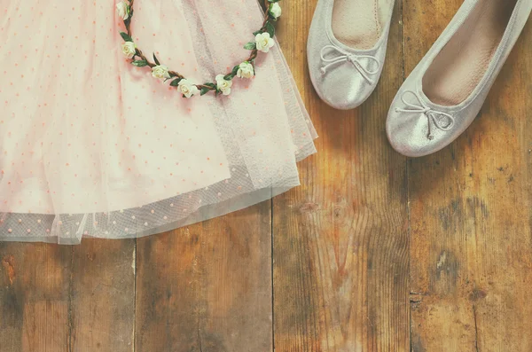 Vestido da menina chiffon vintage, tiara floral ao lado de sapatos de balé em fundo de madeira. imagem filtrada vintage — Fotografia de Stock