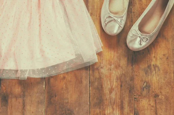 Vintage meisje van chiffon jurk naast ballet schoenen op houten achtergrond. Vintage gefilterde afbeelding — Stockfoto