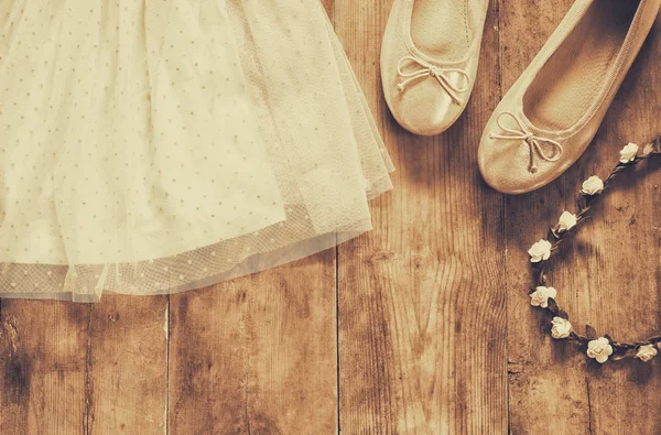 Vestido da menina chiffon vintage, tiara floral ao lado de sapatos de balé em fundo de madeira. vintage filtrado, imagem estilo sépia — Fotografia de Stock