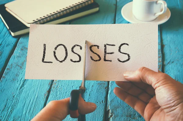 Man hand met kaart met de verliezen van het woord. concept is snijden verliezen en kosten. afbeelding van de retro-stijl — Stockfoto