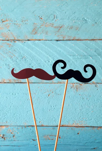 Paper mustaches in sticks in front of wooden background. vintage filtered image — Stock Photo, Image