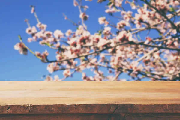 Table rustique en bois devant un arbre en fleurs de cerisier blanc printanier. image filtrée vintage. affichage du produit et concept de pique-nique — Photo