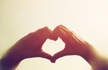 eller karşı günbatımı gökyüzü kalp şeklinde görüntü. Filtre vintage