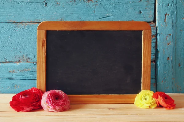 Flowers next to empty blackboard — Stock Photo, Image