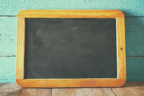 Vintage wooden blackboard on wooden table with space for text — Stock Photo, Image