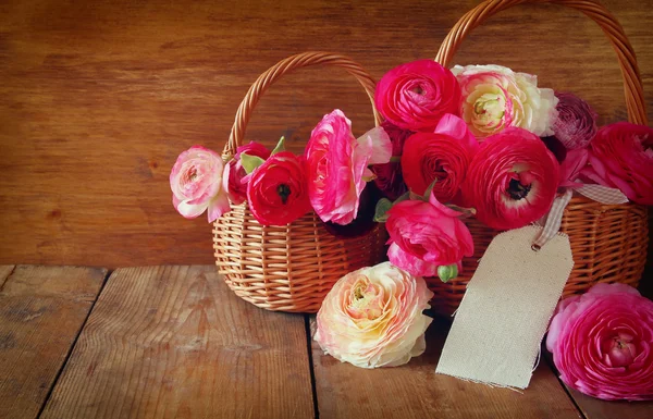 Flores cor-de-rosa na cesta ao lado do cartão vazio, na mesa de madeira . — Fotografia de Stock