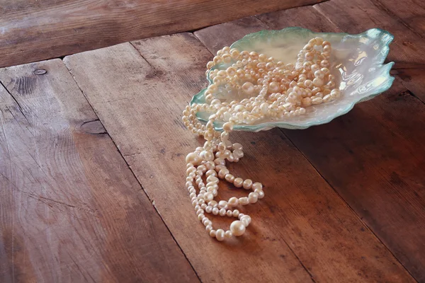 White pearls necklace on grunge wooden table — ストック写真