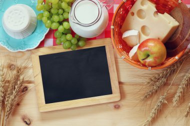 image of dairy products and fruits next to empty blackboard. Symbols of jewish holiday - Shavuot