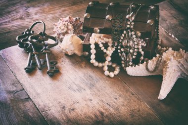 white pearls necklace in treasure chest next to seashells