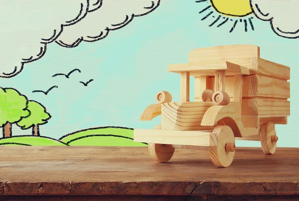 Mobil mainan kayu di atas meja dan latar belakang sketsa lansekap — Stok Foto