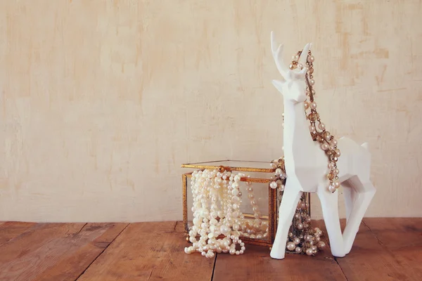 Collana di perle bianche e cervo bianco sul tavolo di legno — Foto Stock