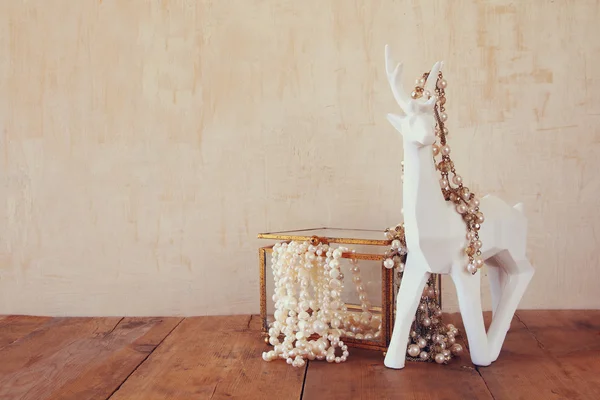 Collier perles blanches et cerf blanc sur table en bois — Photo