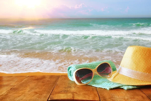 Fedora hoed en zonnebril op houten tafel en zee — Stockfoto