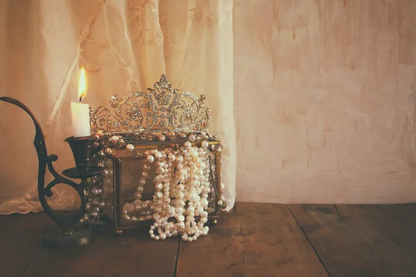 Corona reina de diamantes, perlas blancas junto a la vela ardiente —  Fotos de Stock