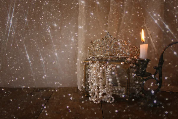 Corona reina de diamantes, perlas blancas junto a la vela ardiente —  Fotos de Stock