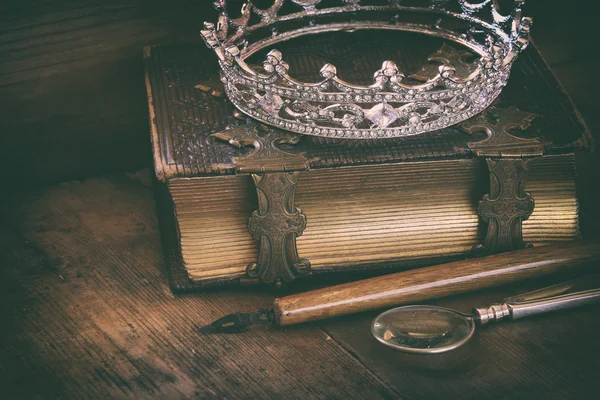 Низко ключевое изображение алмазной королевы короны на старой книге — стоковое фото