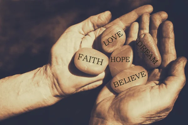 Old man hands holding river stones with words written — Stock Photo, Image