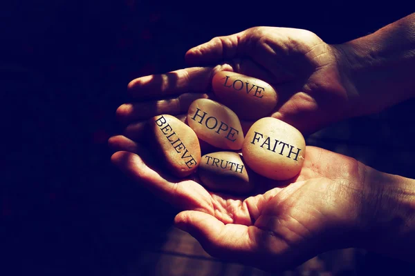 Old man hands holding river stones with words — Stock Photo, Image