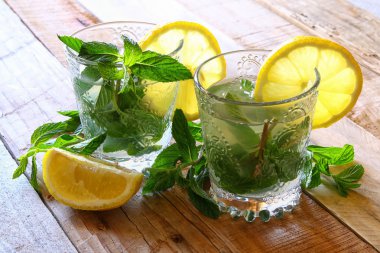 taze mojito ve dilimlenmiş limon bir rustik ahşap tablo.