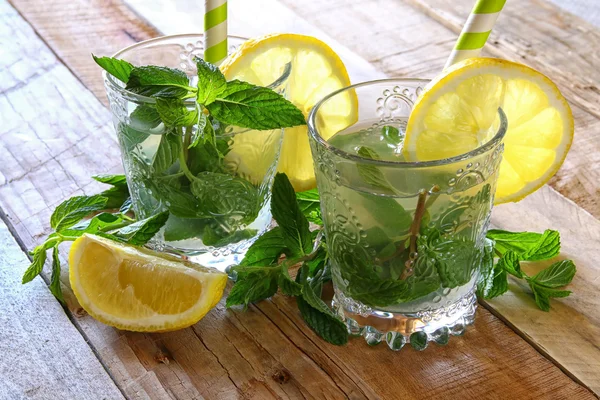 Frischer Mojito und geschnittene Zitronen auf einem rustikalen Holztisch. — Stockfoto