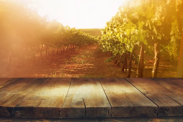 Деревянный стол перед виноградником на закате — стоковое фото