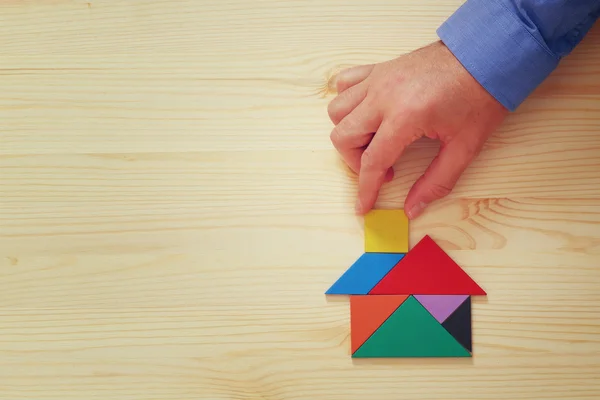 Man's hand pointing at house made from tangram puzzle — Stock Photo, Image