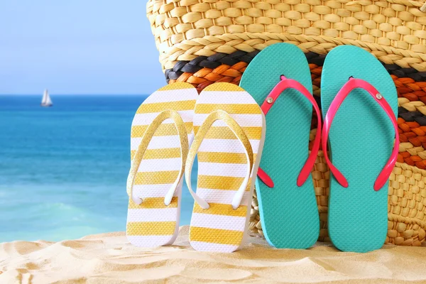 Tropical sandy beach, straw bag and and flip flops Royalty Free Stock Images