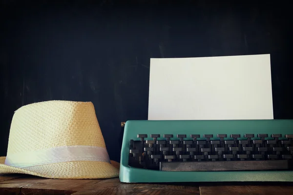 Máquina de escribir vintage con página en blanco al lado del sombrero fedora — Foto de Stock