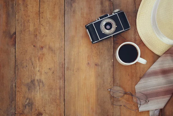 Vintage camera, glasses and fedora hat on wooden table