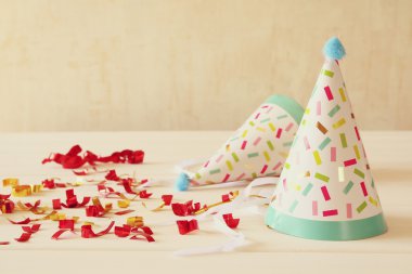 Ahşap masa üzerinde renkli konfeti yanındaki parti şapka