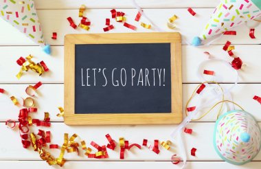 Renkli konfeti ve boş yazı tahtası yanındaki parti şapka