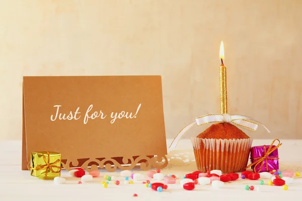 Concepto de cumpleaños con cupcake y vela junto a la tarjeta de felicitación — Foto de Stock