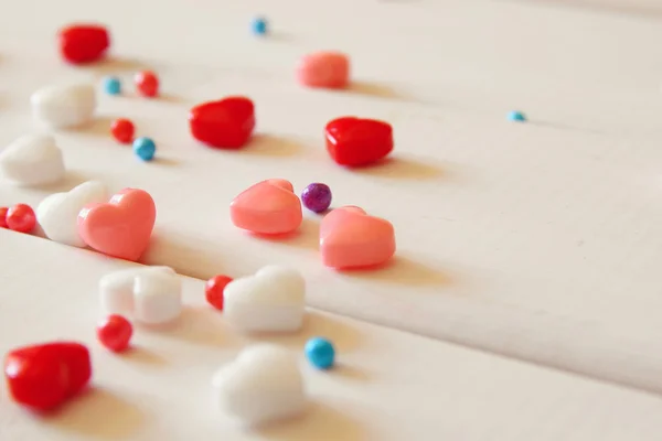 Rote, rosa und weiße Herzen formen Bonbons auf Holztisch — Stockfoto