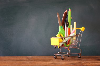 Yazı tahtası önünde okul kaynağı ile alışveriş sepeti