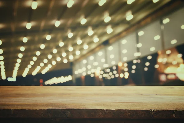 Wooden table in front of abstract blurred resturant lights — Stockfoto