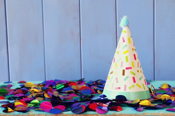 Partyhut und buntes Konfetti auf Holztisch. — Stockfoto