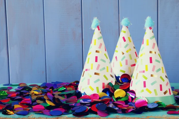 파티 모자와 나무 테이블에 화려한 색종이. — 스톡 사진