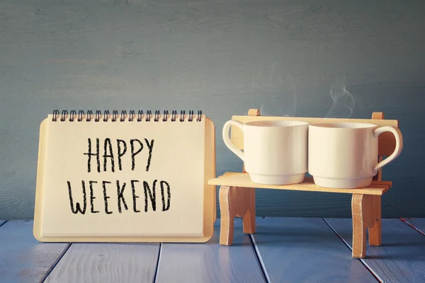 Tazas de café junto a cuaderno con frase "feliz fin de semana " — Foto de Stock