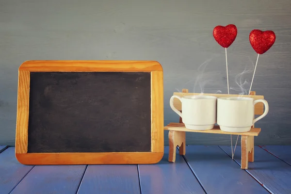 Couple coffee cups next to empty blackboard — Stock Photo, Image