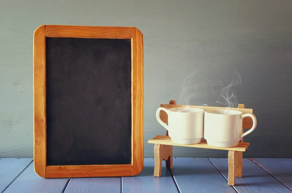 Un par de tazas de café al lado de pizarra vacía —  Fotos de Stock