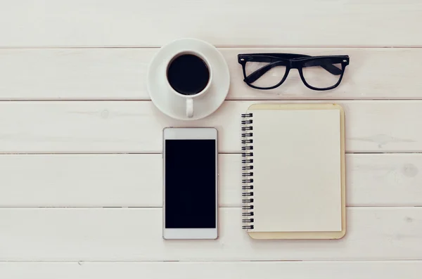 Notebook em branco, celular e xícara de café sobre mesa de madeira — Fotografia de Stock