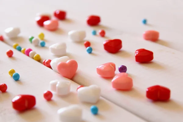 Corazones rojos, rosados y blancos dan forma a caramelos en mesa de madera —  Fotos de Stock